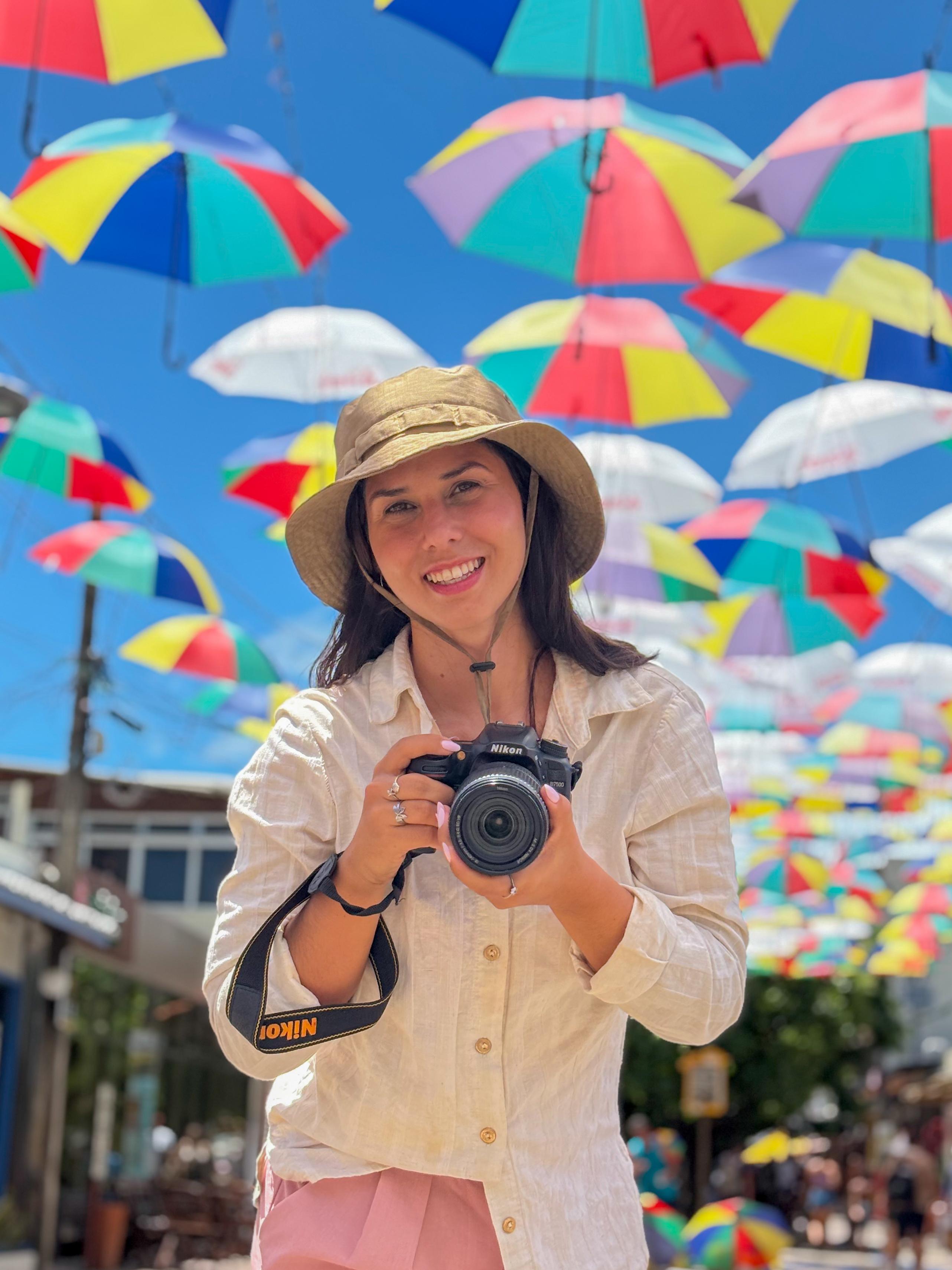 Carol Oliva, fotógrafa, na praia com câmera na mão